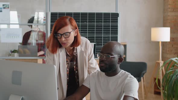 Multiethnic Man and Woman Discussing Alternative Energy Project on Computer