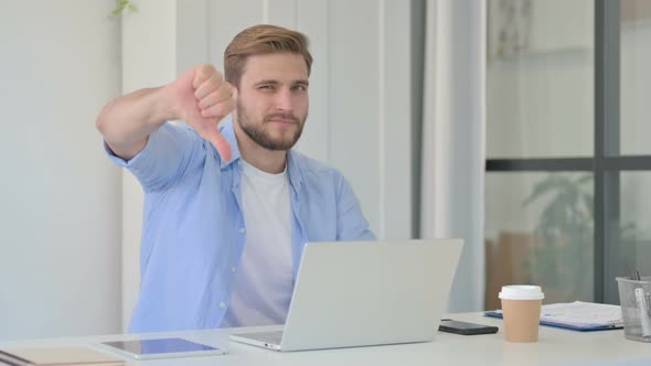 Thumbs Down By Young Creative Man with Laptop in Office