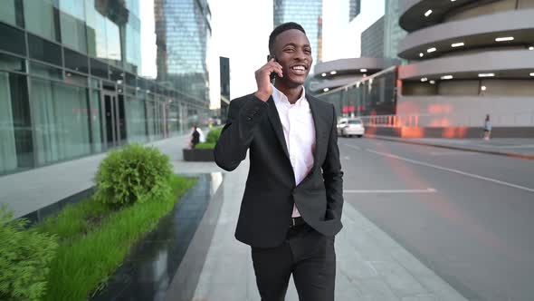 Young black guy walking in the business center and talking on the phone