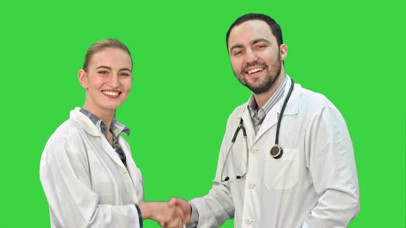 Young Man Doctor and Beautiful Nurse Shaking Hands After Successful Operation and Looking at Camera