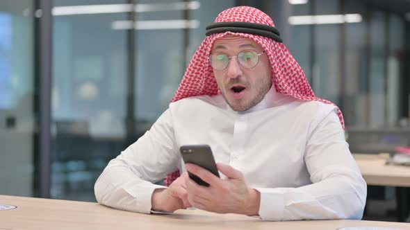 Middle Aged Arab Man Celebrating Success on Smartphone in Office