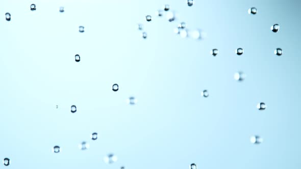 Super Slow Motion Shot of Various Water Drops Falling on Light Blue Background at 1000Fps