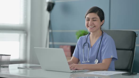 Indian Female Doctor Smiling at Camera while using Laptop in Office