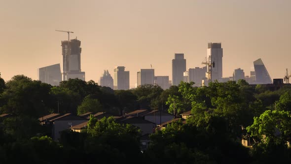 Rising up to reveal Austin, Texas downtown skyline buildings during hazy summer sunrise at golden ho