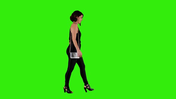 Pretty woman walking for a date night over green screen in long shot.