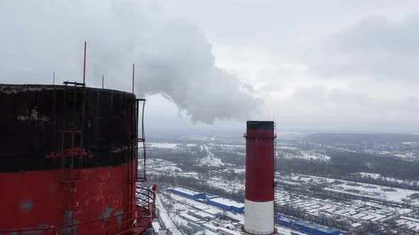 Aerial Survey Over the Tops of Two Smoking Factory Pipes and the Snow-capped City Lying Below