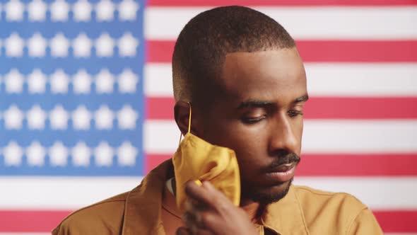 Joyous Black Man Taking Off Face Mask against American Flag