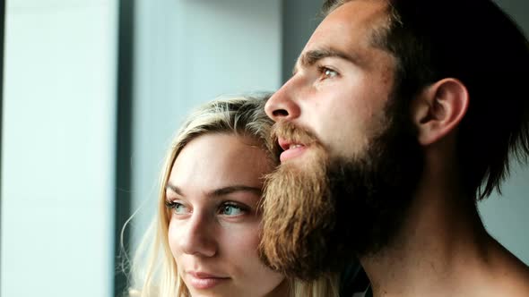 Couple looking through window at home 