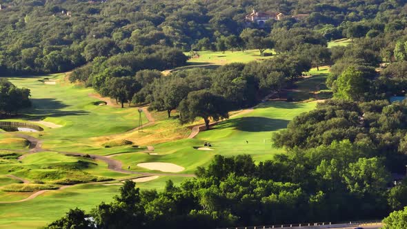 Golfer playing Austin Country Club takes swing on 3rd hole fairway during summer morning with aerial