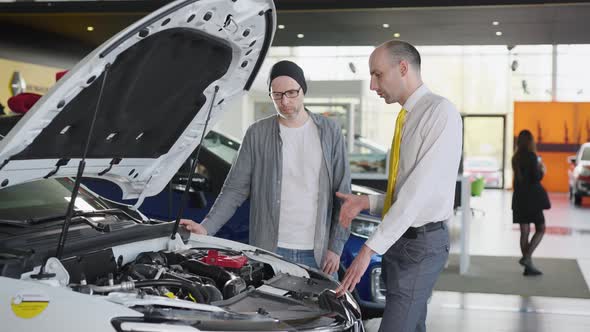 Sales Manager and Client Near a New Car with an Open Hood