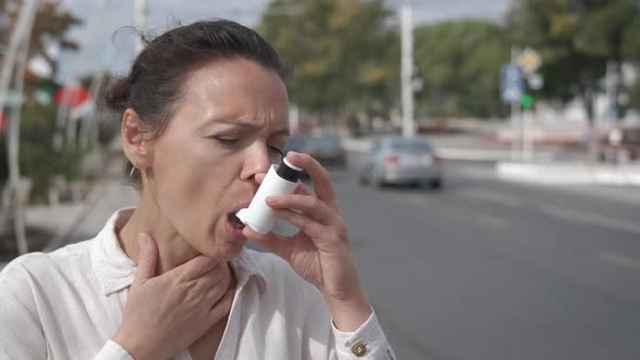 Woman with inhaler in the city street. 