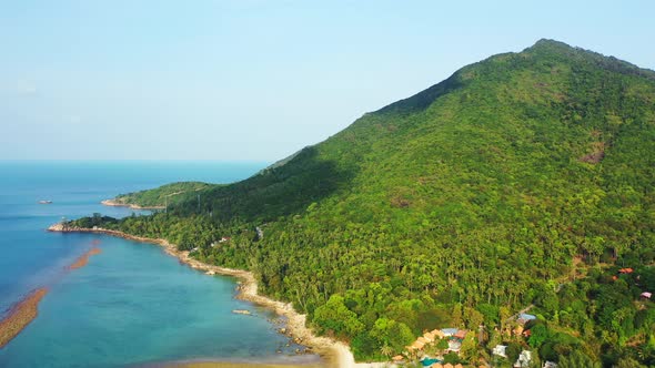 Tropical rocky coast with exotic vegetation on the hills, emerald calm lagoon. Summer vacation backg