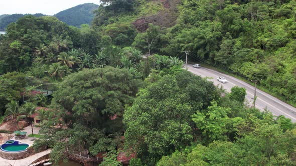 Aerial view of traffic on mountain road surrounded by Lush vegetation, Along Coastline. Brazil