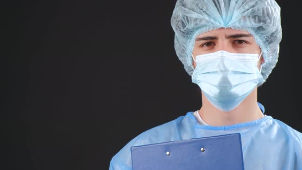 Serious Man in a Blue Medical Coat and Medical Mask Looking at Camera