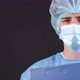 Serious Man in a Blue Medical Coat and Medical Mask Looking at Camera - VideoHive Item for Sale