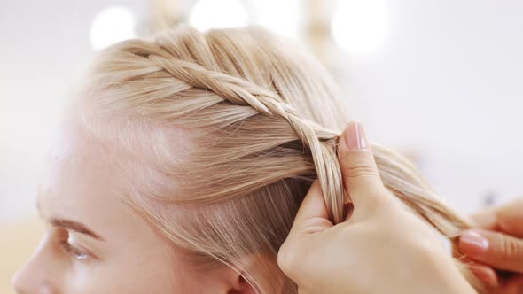 Hairdresser Plaiting Braids to Blonde Girl in Beauty Salon Slow Motion Close Up