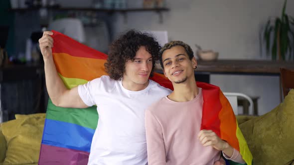 Guys Spend Time Together at Home on the Couch Under Lgbt Colorful Rainbow Flag