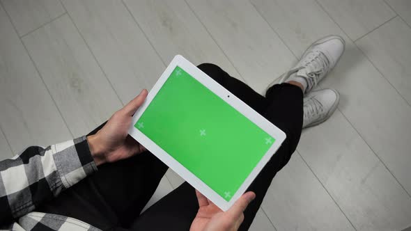 Man Sitting on Chair Looking at Digital Tablet with Green Screen Chroma Key