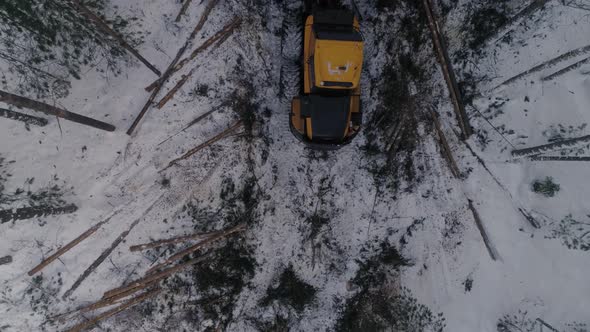 Top down Aerial view of Forest Forwarder stacks tree logs in the winter forest. 24