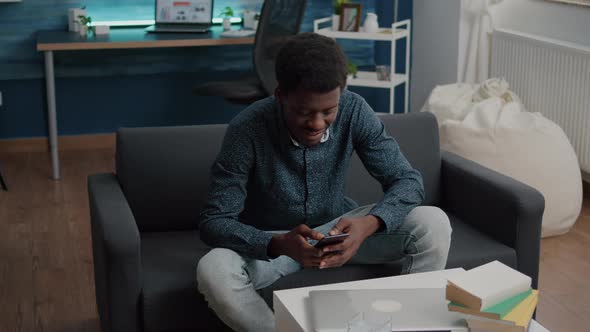 Black Guy in His Living Room Using Phone to Browse Social Media