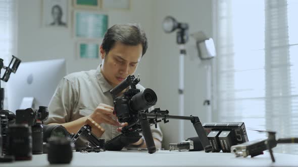 An Asian man is setting up a camera rig 