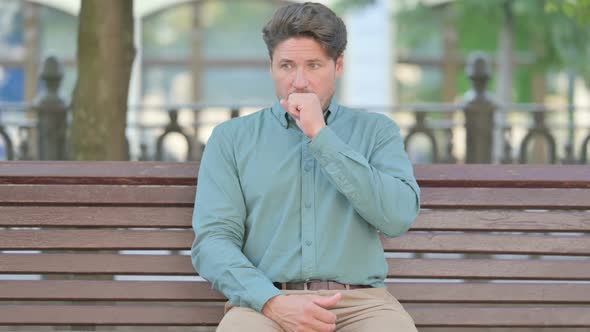 Middle Aged Man Coughing While Sitting Outdoor