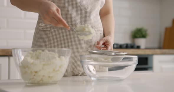 Young Woman Puts Cottage Cheese in Bowl at Home Kitchen