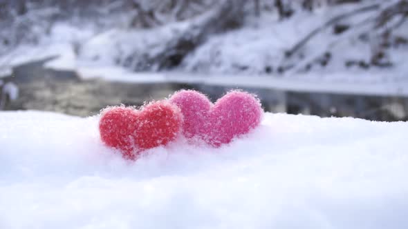 Red and Pink Woolen Hearts on White Snow on the River Shore in Winter