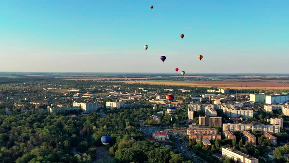 Multicolored balloons fly over trees