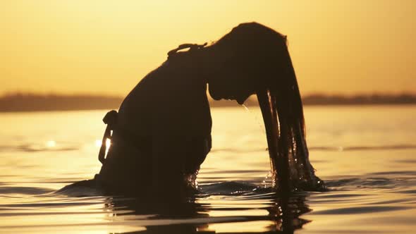 Silhouette of Woman Flipping Her Long Hair Back in Water. Slow Motion 240 Fps