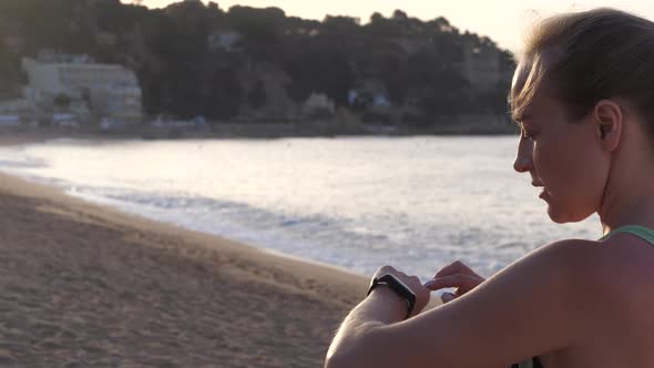 Woman Using Fitness Bracelet Training on Beach