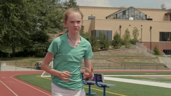 teen girl athlete running track sprints towards the camera in slow motion