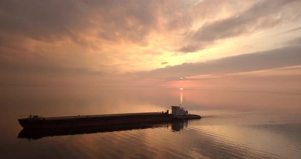 A Large Cargo Ship Sailing With Cargo On The River In The Evening During Sunset