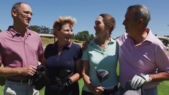 Senior people holding golf clubs talking to each other at golf course