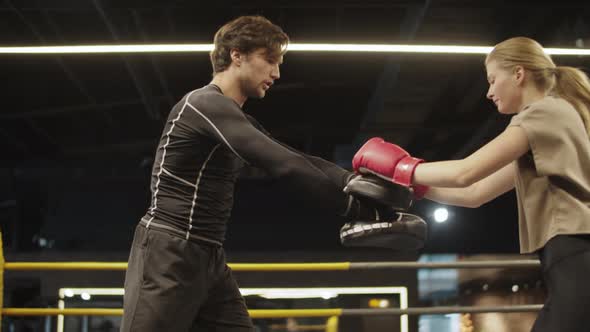 Sport Couple Training on Boxing Ring. Fit Girl Practicing Leg Hits in Sport Club