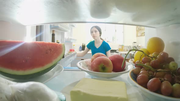 POV shot from inside a refrigerator of girl opening the door and taking out food