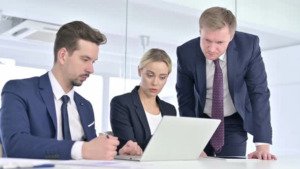 Serious Professional Team Discussing and Working on Laptop