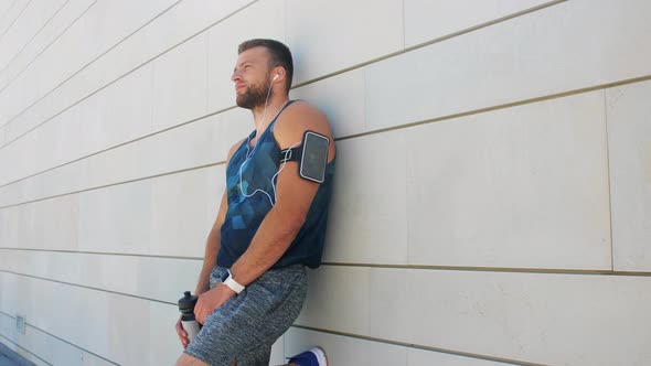 Man in Earphones with Smartphone Drinking Water