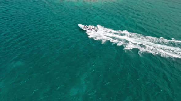 Speedboat with tourists on board navigating along Playa Ensenada beach leaving white wake, Dominican