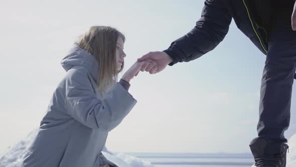 Handsome Blond Bearded Man Giving Hand To Attractive Young Woman Helping Her To Climb on the Ice