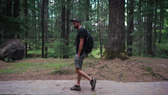 A Wide Angle Following Shot of a Young American Guy Walking on a Forest Path