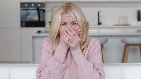 Shocked Frightened Senior Woman Covering Mouth with Hand and Looking Terrified at Camera Indoors