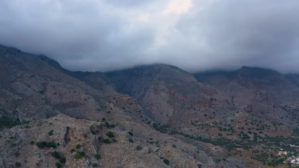 Flying above Mountains in Greece. Aerial view of Stormy clouds cover Mountain. Clouds above gorge 