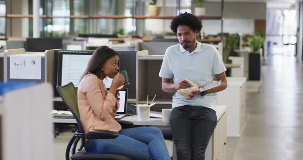 Video of diverse businesswoman and businessman drinking coffee, eating and talking in office