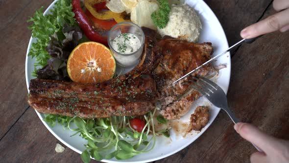 Cutting Pork T Bone With Knife And Fork Meat And Bone Steak With Salad And Mashed Potato Top View