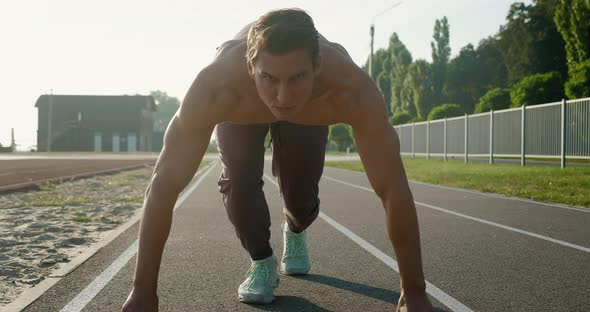 Young Muscular Concentrated Athlete Man Starting Running of the Treadmill at the Stadium