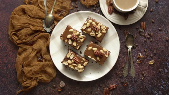 Chocolate Cake with Caramel Frosting, Pecans and Hot Coffee, on Rustic Background. Freshly Baked