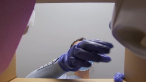 Woman in Mask Taking Cleaning Supplies From Box