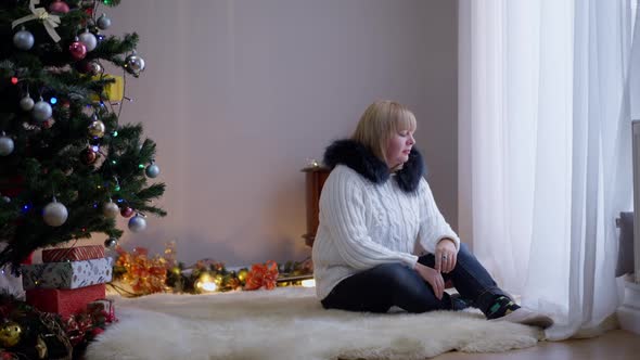 Frustrated Sad Woman Crying Alone on Christmas Eve As Santa Clause Entering Living Room with Present