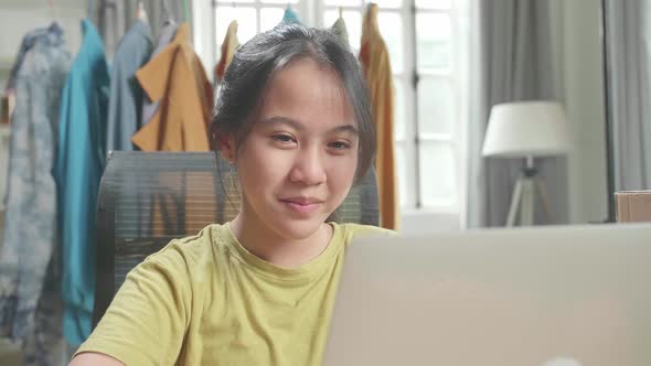 Close Up Of Asian Young Girl Online Seller Looking At Computer Screen While Selling Clothes At Home